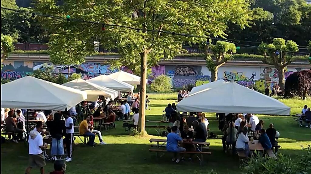 Staden in Saarbrücken: Wiese mit Bierbänken und vielen Leuten im Sommer – entspannte Stimmung am Saarufer